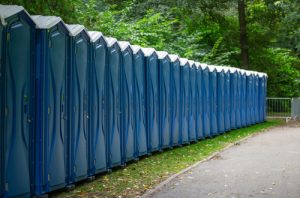 line of portable toilets on grass next to walkway